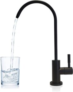 Llenar un vaso de agua en la mano del grifo de la cocina